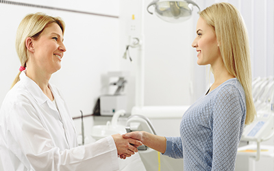 A dentist shaking a female patient's hand